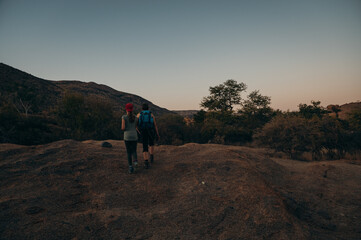 Frau wandert zusammen mit Tochter bei Sonnenuntergang durch das Erongo Gebirge, Namibia
