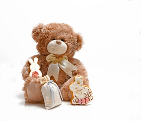 Teddy bear with Easter gifts, with a yellow bow,  on a white background