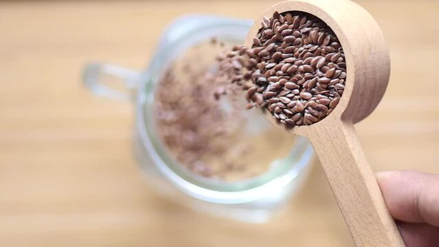  slow motion of pouring flax seeds into a glass of water 