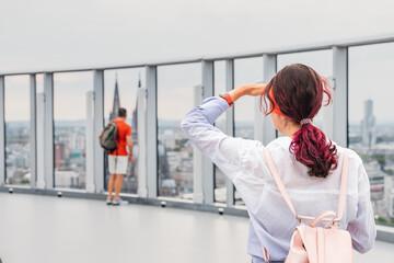 A tourist girl admires the scene on the panoramic touristic viewpoint at the top of a skyscraper in...