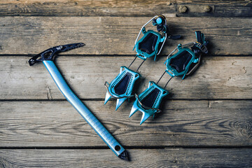 Ice axe and crampons on a wooden background. Climbing and mountaineering equipment. Ice climbing...