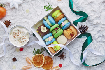 Fototapeta na wymiar Box of aesthetic colorful sweet macaroons, gift for Christmas among winter decorations and coffee