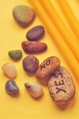 Obraz premium Various pebbles for fortune telling YES or NO on a yellow table