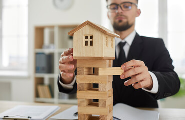 Close up of little miniature wooden toy house with tower foundation where young entrepreneur...