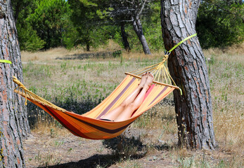 feet of the girl having a rest in the hammock in the summer in the resort village in the summer