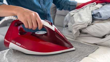 close-up of a woman's hand ironing laundry on an ironing board