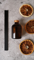 Citrus reed diffuser on dark background. Bottle, sticks and dry oranges
