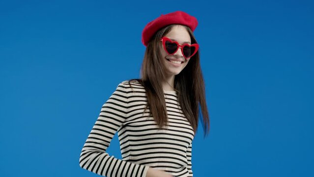 Fashionista woman asks join her, beckons with inviting hand hugs gesture. Young lady calling - Hey you, come here. Hipster teenager, playful, inviting to come. Blue studio background