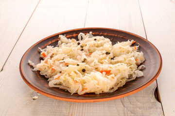 Sauerkraut in a clay plate on a wooden table, macro.