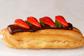 Eclair with chocolate cream, mint, strawberry on white background