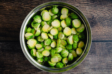 Halved and Trimmed Raw Brussels Sprouts in a Mixing Bowl: Uncooked Brussels sprouts tossed in a metal mixing bowl