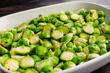 Low Angle View of Halved Brussels Sprouts Tossed in Extra Virgin Olive Oil: A baking dish full of raw Brussels sprouts cut in half and tossed in olive oil, salt and pepper
