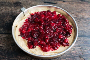 Spiced Cake Batter Topped with Cranberry Sauce in a Round Cake Pan: Freshly made cranberry sauce spread over unbaked cake batter