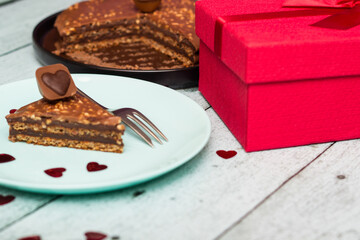 Chocolate cake served for two with gift for Valentine's Day. On wooden rustic table
