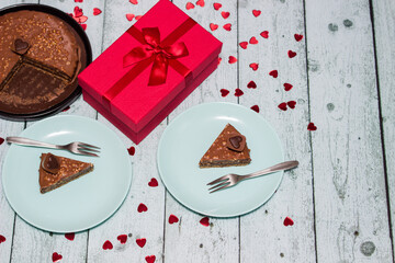 Chocolate cake served for two with gift for Valentine's Day. On wooden rustic table