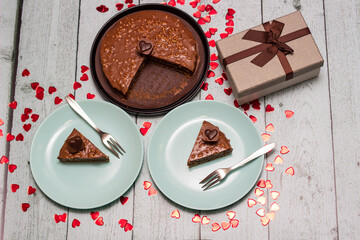 Chocolate cake served for two with gift for Valentine's Day. On wooden rustic table