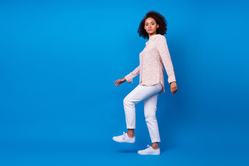 Full length photo of shiny charming lady wear pink shirt walking up stairs empty space isolated blue color background