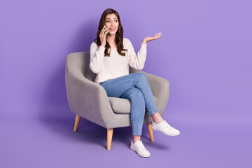 Photo of excited pretty positive lady sit chair empty space speaking telephone device friends family isolated on purple color background