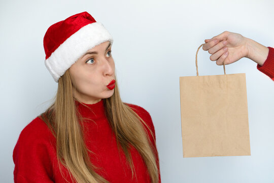 A beautiful girl dressed as Santa contemptuously looks at the gift.