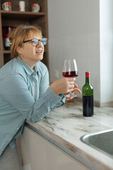 Woman drinking a glass of wine in a modern kitchen