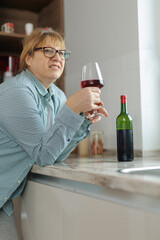 Woman drinking a glass of wine in a modern kitchen