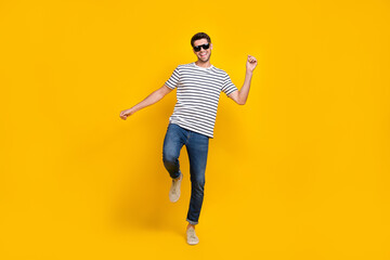 Fototapeta na wymiar Full length photo of funky cheerful man wear white t-shirt dark glasses having fun dancing isolated yellow color background