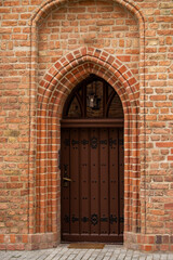 Old wooden door in a brick wall. Arch
