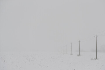 Winter fog with snow and high voltage poles