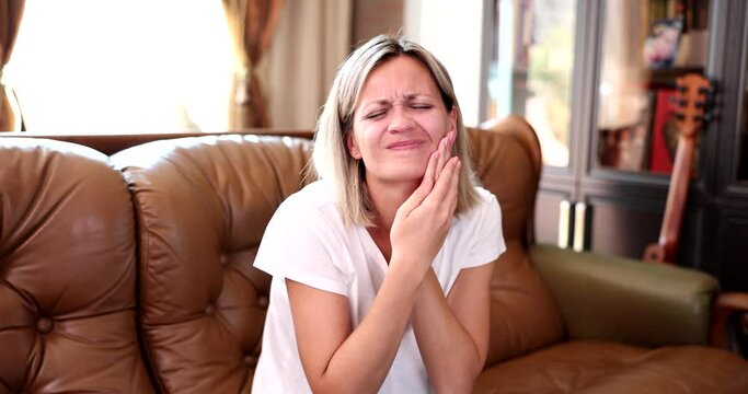 Beautiful young woman suffering from terrible severe pain in teeth and touching cheek with hand