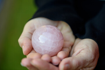 Esfera de cuarzo rosa sostenido por las manos de una chica. © peredapatri