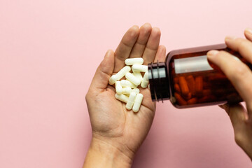 Zinc tablets in the hand on a pink background.