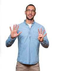 Happy young man doing a number nine gesture with his hands