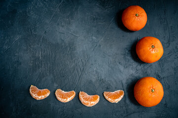 Tangerine full fruits and slices isolated on dark slate background. view from above with copy space for text