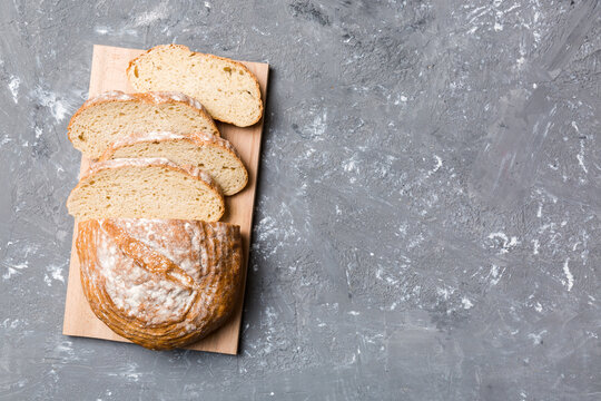 Freshly baked bread slices on cutting board against white wooden background. top view Sliced bread - Powered by Adobe