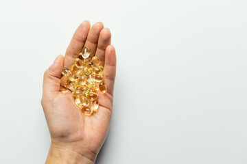 Vitamin D3 capsules on the hands. White background, space for text.