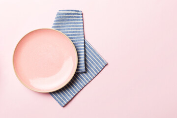 Top view on colored background empty round pink plate on tablecloth for food. Empty dish on napkin with space for your design