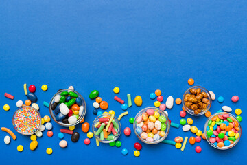 different colored round candy in bowl and jars. Top view of large variety sweets and candies with copy space