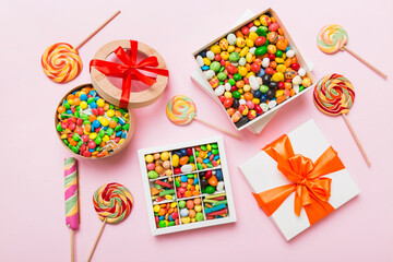 Set of different sweet candy in a paper box with a satin ribbon on a colored background. Holiday concept