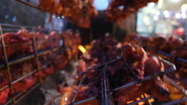 Close up 5 rows of grilled chicken ayam golek rotate burn by charcoal fire. Delicious Malaysia street food