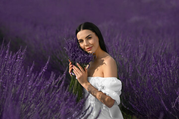 Beautiful young woman with bouquet in lavender field