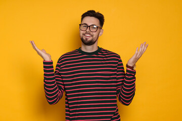 Handsome man in striped sweatshirt and eyeglasses on yellow background