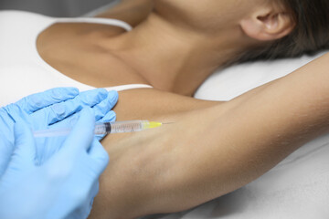 Young woman getting armpits injection in salon, closeup