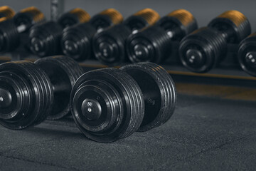 Obraz na płótnie Canvas Heavy dumbbells weighing 50 kilograms. Sports equipment and dumbbells. Interior of the gym. Camera focus on the dumbbells lying on the floor