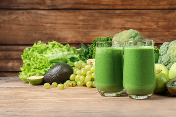 Glasses of fresh green smoothie and ingredients on wooden table, space for text