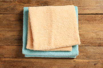 Soft folded colorful terry towels on wooden table, top view - obrazy, fototapety, plakaty