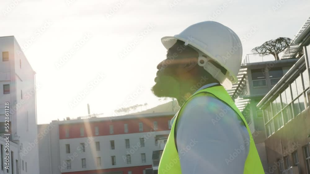 Poster young construction manager looking around at the buildings on the work site while putting on a helme