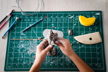Children making shark sculpture with grey clay on kraft cutting mat with some claying implement