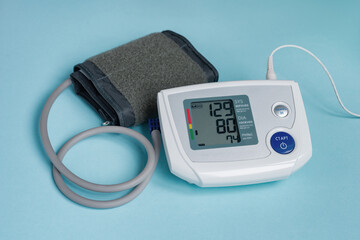 Blood pressure measuring device, tonometer on blue medical background. Electronic digital tonometer. Headache, treatment of hypertension and hypotension. Office of the therapist.