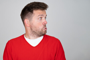 Obraz premium Caucasian manlooks with hesitsation aside, with copy space for your text