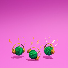 Three green Christmas baubles with headphones and musical notes on a vibrant purple background. Concept of Christmas, New Year and winter holidays party, music and happiness. Good Vibes.
